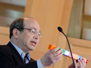 Neil Aronin verwendet riesige Legostein, um zu erklären, wie Gen-Stummschaltungs-Medikamente in kleinere Moleküle mit ihren eigenen Nebenwirkungen aufbrechen könnten. Image Credit: Lev Blumenstein for CHDI