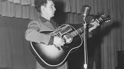 Woody Guthrie, die vielleicht berühmteste Person, die an der Huntington-Krankheit erkrankt war, war ein Folkmusiker mit einer Gitarre mit der Aufschrift "Diese Maschine tötet Faschisten". In Anlehnung an Gutrhies Gitarre sagte Ed: "HDBuzz war schon immer eine Maschine, um Hoffnung in Taten umzusetzen."  